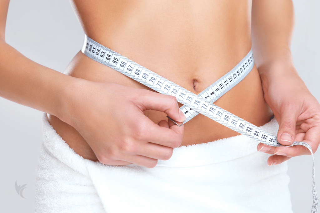 Fit woman holding tape measure around tummy